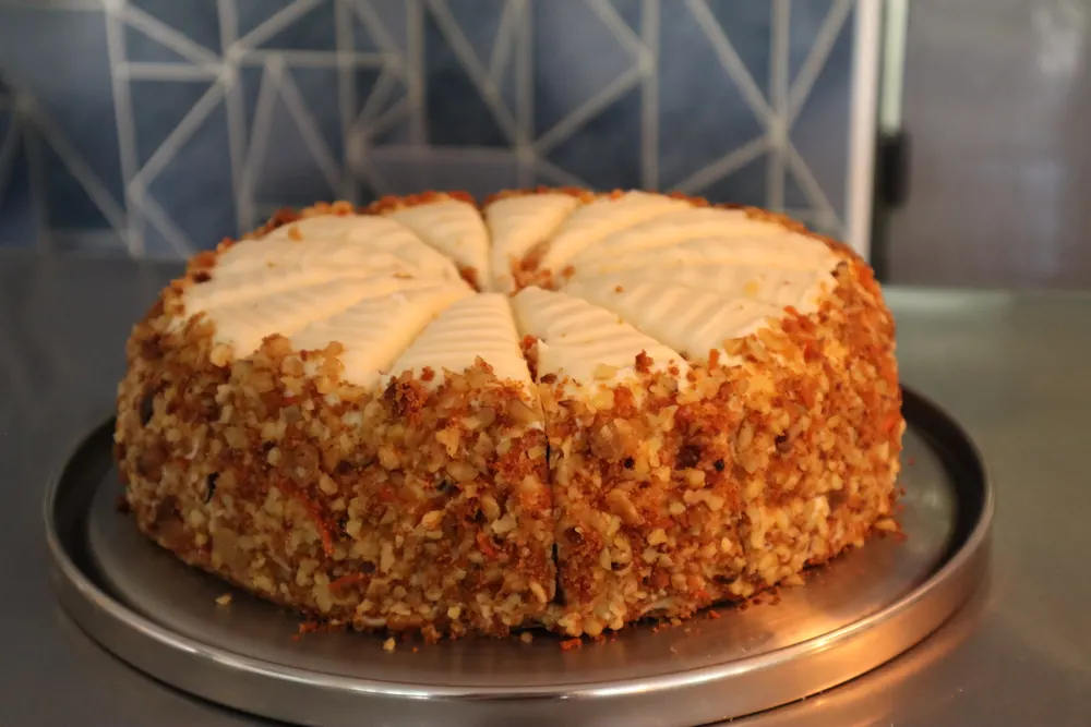 A walnut-crusted cream cake on a stand
