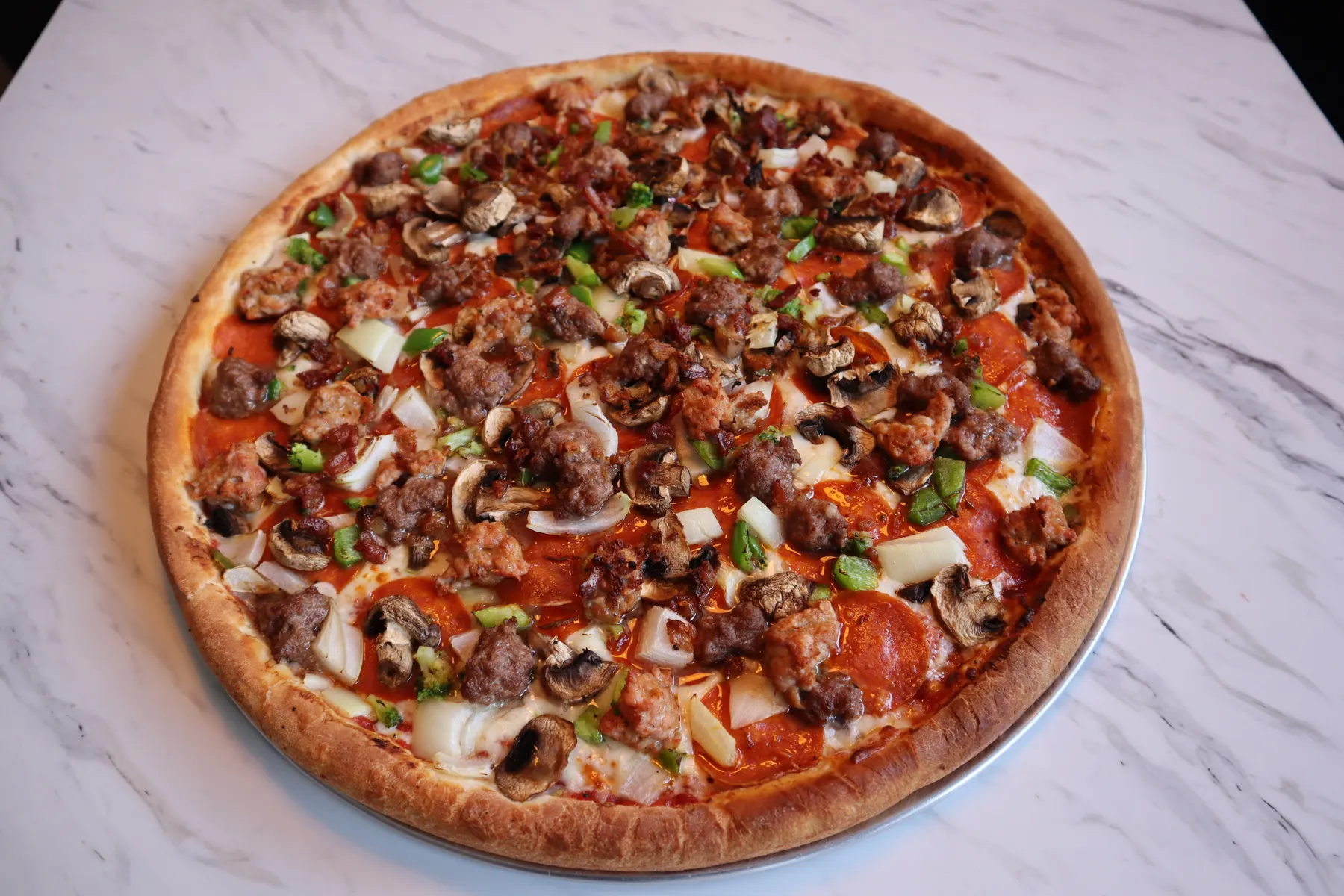 A loaded specialty pizza fresh from the oven at Stavros Pizza