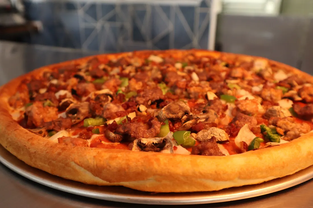 A loaded specialty pizza with meats and vegetables