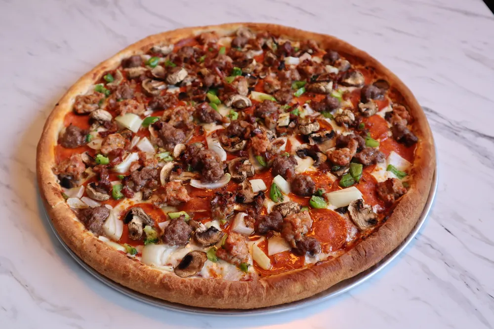 A whole specialty pizza on a marble counter